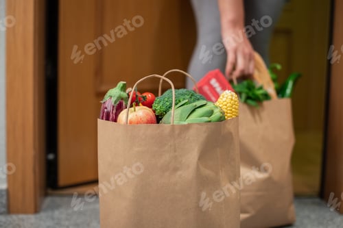 Preview: A woman picks up a bag of food at the door of her house. Coronavirus. Quarantine. Stay at home