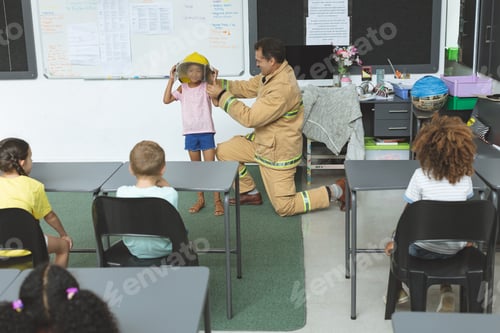 Preview: firefighter teaching to schoolgirl about fire safety in classroom