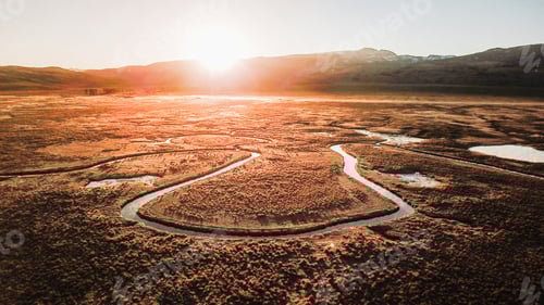 Preview: Scenic view of a river flowing through fields on a mountainous background