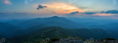 Preview: Fantastic sunrise or sunset over green mountain ridge covered with dense blue fog.