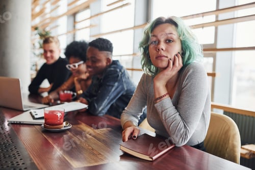Preview: Alternative girl with green hair is sitting against group of multi ethnic people