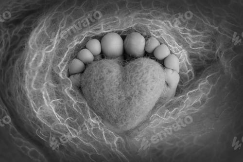 Preview: Toes and feet of a newborn. Knitted heart in the legs of baby.