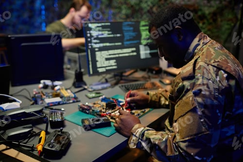 Preview: Young serious African American male security officer repairing circuit board