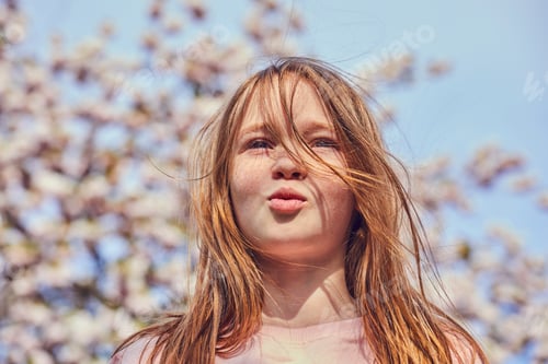 Preview: Young girl enjoying a spring day among blossoming cherry trees