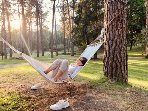 Preview: Middle aged woman lying on hammock in park in summer