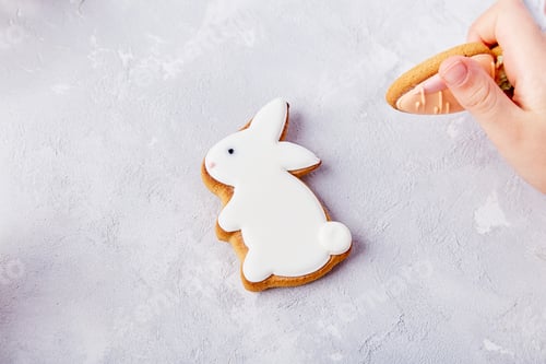 Preview: Child hand holds carrot cookie and rabbit cookie backdrop. Happy Easter background