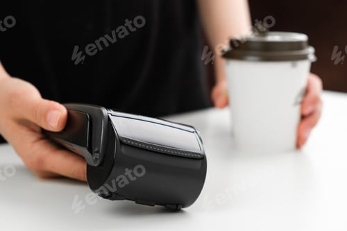 Preview: Woman gives POS terminal for paying a coffee in a coffee shop