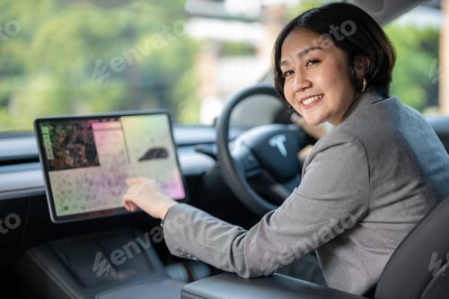 Preview: A woman is sitting in a car and looking at a screen