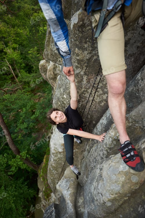 Preview: woman climbing rock trekking outdoors. Carefree hiker smiling her friend. Friendly helping hand