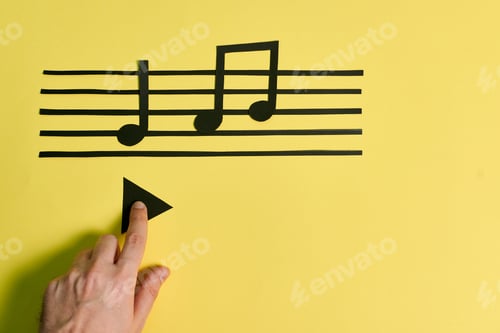 Preview: A man's hand touches the play button on a yellow background. Music concept