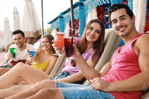 Preview: Happy young friends with fresh summer cocktails relaxing on sunbeds