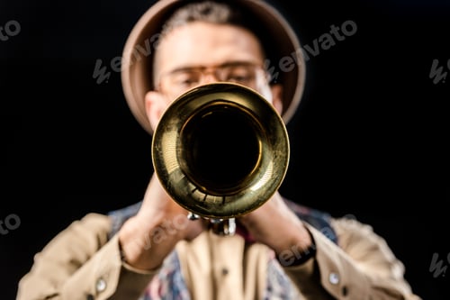 Preview: selective focus of male jazzman playing on trumpet isolated on black