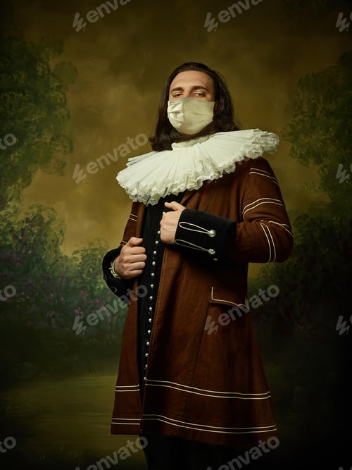 Preview: Young man as a medieval knight on dark background wearing protective mask against coronavirus