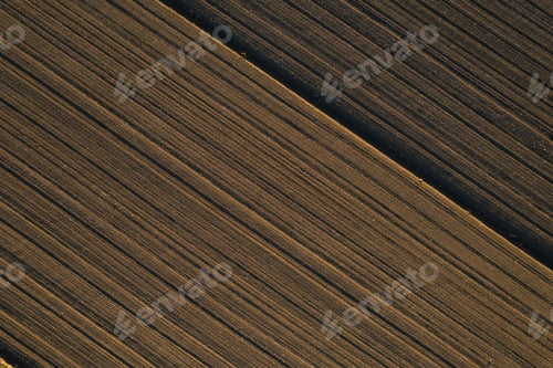 Preview: Aerial view of an empty field at sunset, with recently plowed crops and dirt covering the terrain