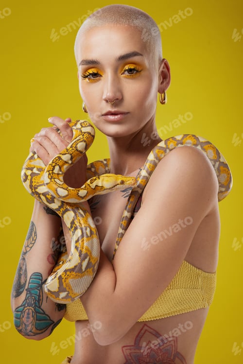 Preview: Shot of a fashionable woman holding a snake while modelling a yellow concept