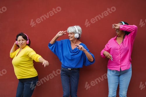 Preview: Happy multiracial senior people dancing to music playlist with wireless headphones outdoor