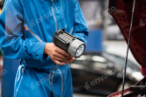 Preview: Mechanic holding flashlight preparing to repair car