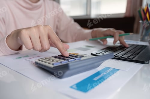 Preview: Close up Business woman using calculator and laptop for do math finance on wooden desk in office and