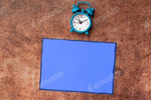 Preview: Isolated alarm clock resting on a hardwood floor beside a blank book with copy space