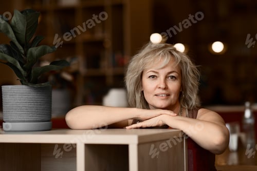 Vorschau: Porträt einer erwachsenen ziemlich lächelnden blonden Frau in einem Café