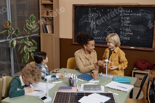 Preview: Female Teacher Showing Wind Turbine Model to Group of Kids in School
