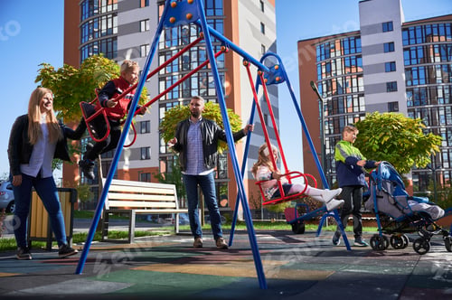 Preview: Large family with four kids by swing set.