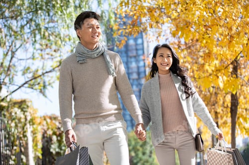 Preview: Happy young Chinese couple with shopping bags on street