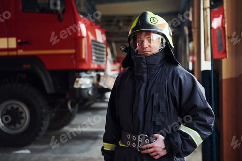 Preview: Male firefighter in protective uniform standing near truck