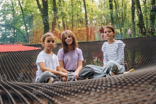 Preview: Front view, sitting and looking forward. Kids are playing on the children's amusement ropes course