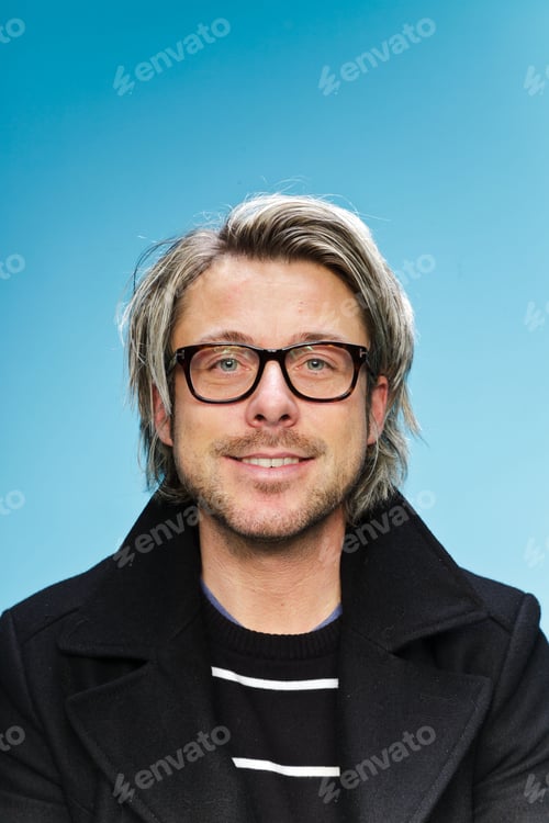 Preview: Studio Portrait Of Young Man With Long Blond Hair Wearing Glasses And Black Jacket. Isolated On