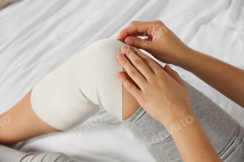 Preview: Young woman with leg wrapped in medical bandage on bed, closeup