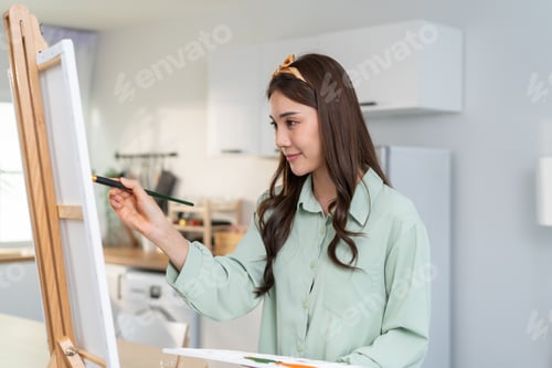 Preview: Asian young talented woman artist coloring on painting board in house.