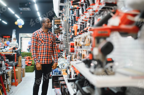 Preview: African americam man buying modern electric drill while standing in tool.