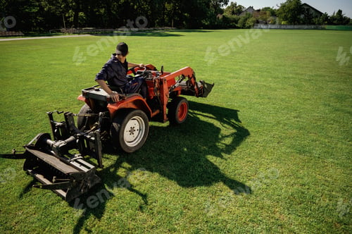 Preview: Loan work. Man is with utility tractor with grass cutter and aerator equipment on the field