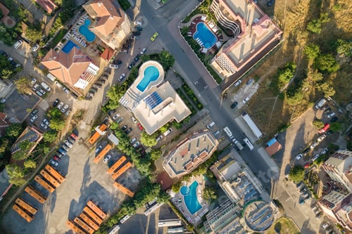 Preview: Top down aerial view of hotels roofs, streets with parked cars and swimming pools