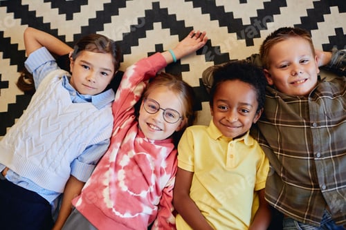 Preview: Diverse Kids Laying on Floor in Classroom Looking Up at Camera