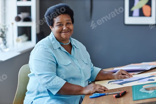 Preview: Happy aged female designer looking at camera while working over new artwork