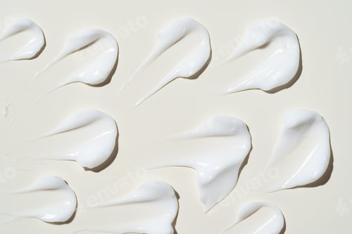 Preview: Texture of white cream on beige background. Smear of moisturizer close up. Lotion swatch.
