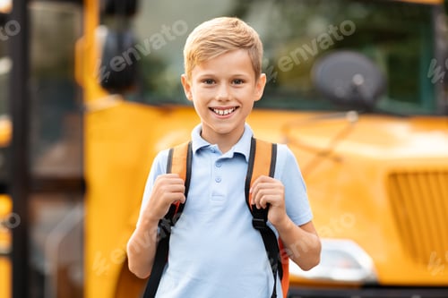 Preview: Smiling cute preteen boy posing near yellow school bus outdoors