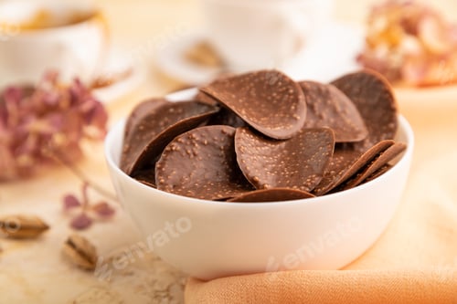 Preview: Chocolate chips with cup of coffee and caramel on a beige concrete background and orange