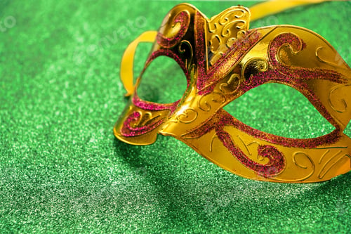 Preview: Golden carnival mask on green shiny background. Mardi Gras concept. Fat Tuesday symbol close-up.