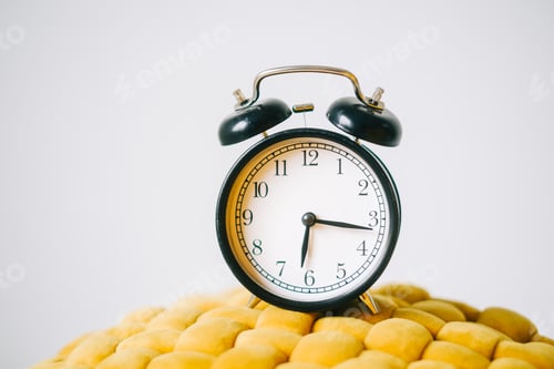 Preview: Black alarm clock on a yellow chair, close up.