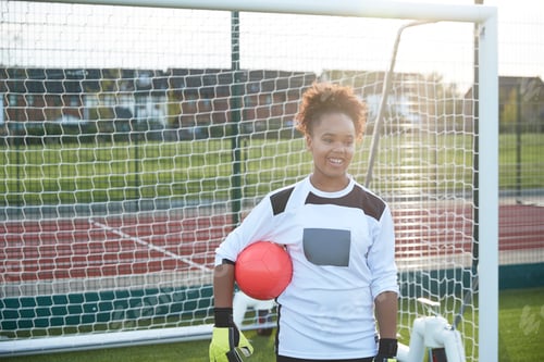 Preview: Young soccer player enjoys a sunny day on the field with a ball in hand.