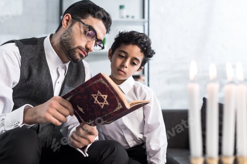 Preview: handsome jewish father and son reading tanakh in apartment