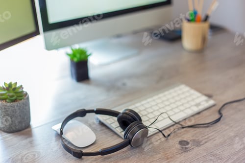 Preview: Closeup shot of earphones and a computer on a wooden table