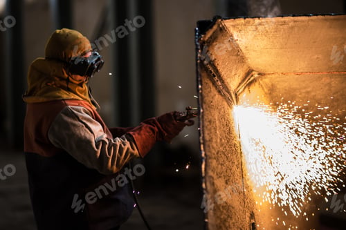 Preview: Demolition construction worker using a flame torch to cut up heavy machinery
