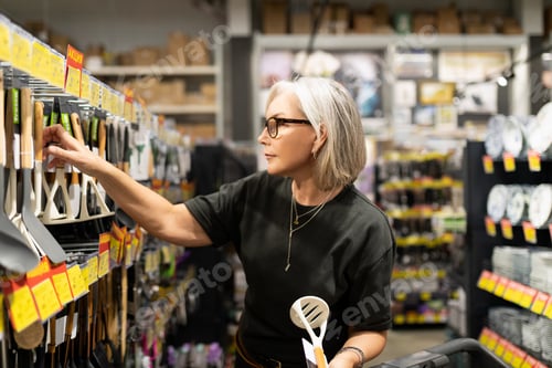Preview: Woman shopping for kitchen utensils in a home goods store during the day