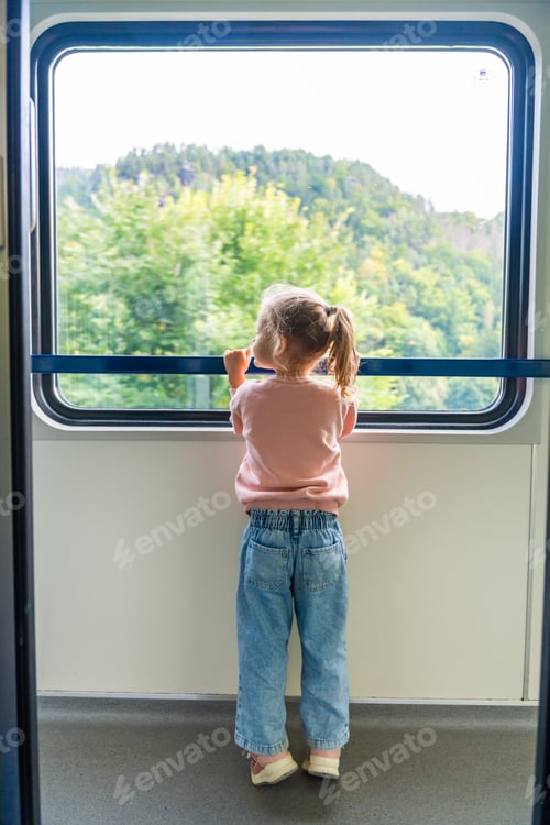 Preview: Little girl looking out train window outside, while it moving. Traveling by railway in Europe