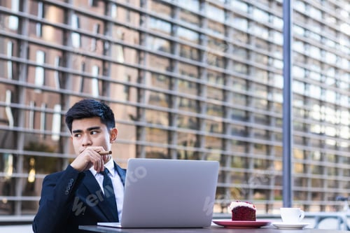 Preview: Young Asian office worker having a breakfast while working on laptop