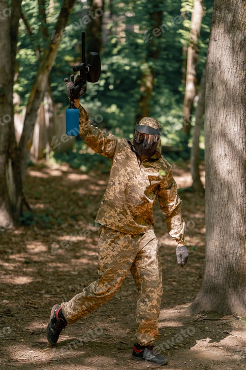 Preview: in the wild crouching near the trees player in a pinball uniform holds a gun with paint balls